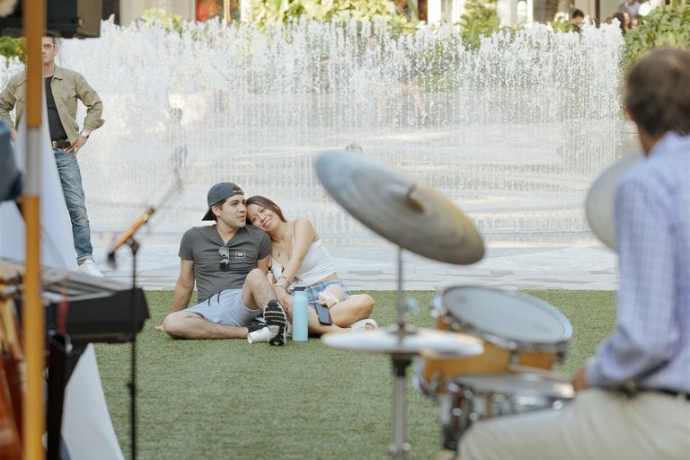 couple sitting on a blanket on the lawn watching a live band