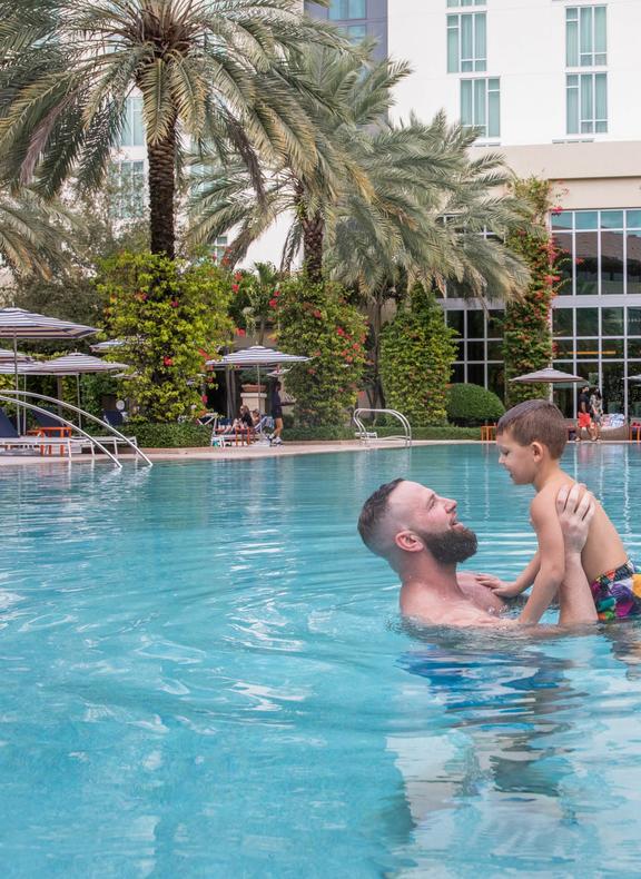 Dad holding young son up in pool