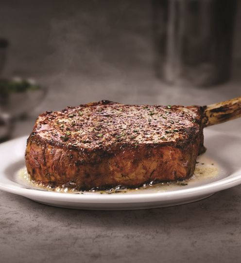 bone-in steak sitting on circular white plate