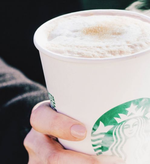 person holding a to-go beverage from Starbucks