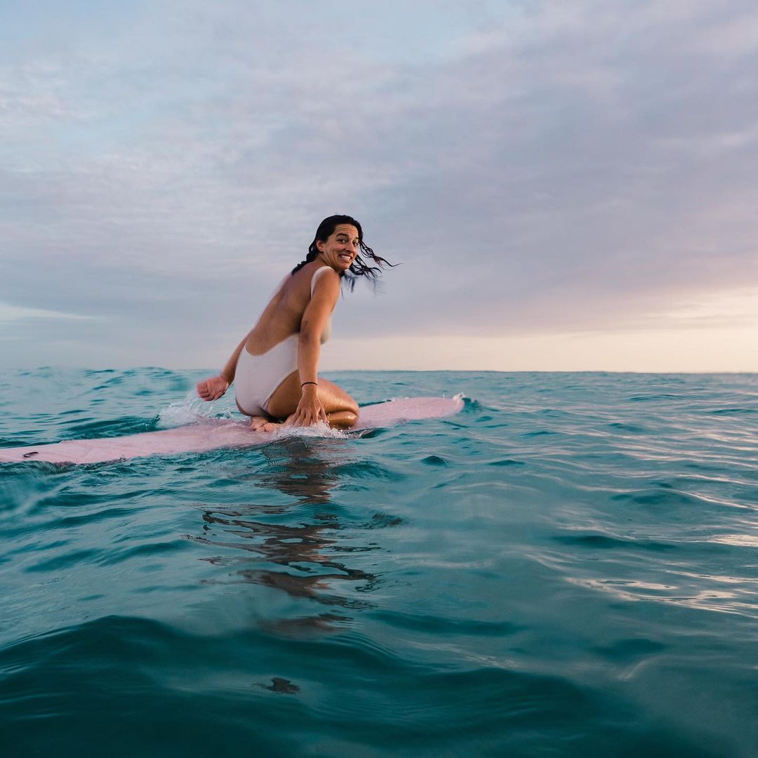 Mary paddling in ocean on pink surfboard