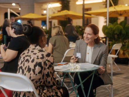 Woman sitting  at a table interviewing another person on the other side of the table