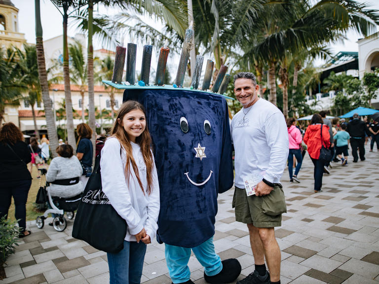 people stand with person in hanukah costume