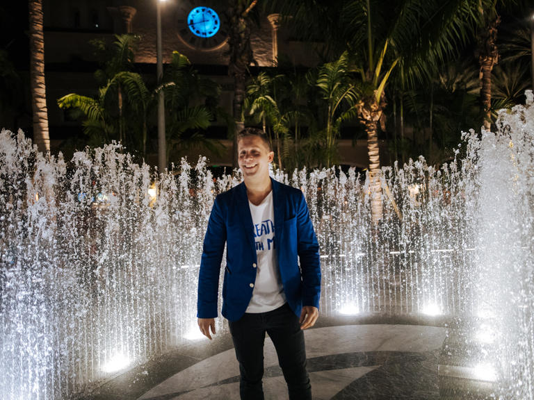 man stands amongst active water fountain